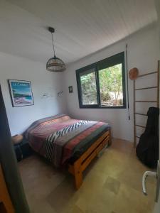 Un dormitorio con una cama en una habitación con ventana. en Maison atypique avec vue unique, en Le Carbet