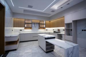 a large kitchen with white counters and wooden cabinets at Villa, 6BR with swimming pool next to Stars avenue in Jeddah