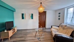 Una sala de estar con un sofá y un televisor. en Entre 2 Jardin Drap compris et Barbecue, en Sarlat-la-Canéda