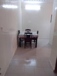 Una mesa y dos sillas en una habitación blanca en Keur Vieux DIATTA, en Ziguinchor