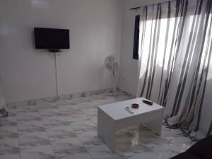 sala de estar con mesa blanca y TV en Keur Vieux DIATTA, en Ziguinchor