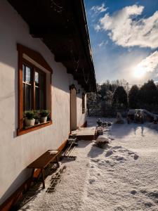 a building with a window and benches in the snow at Ping pong Cottage in heart of Liptov in Jakubovany