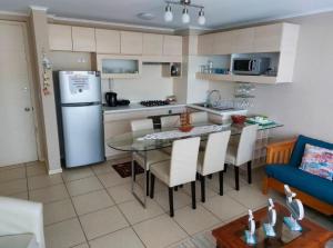 a kitchen and dining room with a table and a refrigerator at Departamento en Condominio Laguna Bahía Algarrobo in Algarrobo