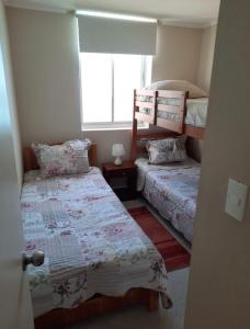 a bedroom with two beds and a window at Departamento en Condominio Laguna Bahía Algarrobo in Algarrobo