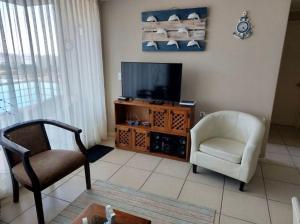 a living room with a television and a chair at Departamento en Condominio Laguna Bahía Algarrobo in Algarrobo