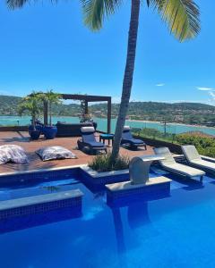 a swimming pool with lounge chairs and a palm tree at Mar Búzios inn in Búzios