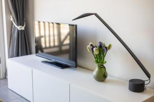 a vase of tulips and a lamp on a white dresser at Plaza in Sint-Idesbald