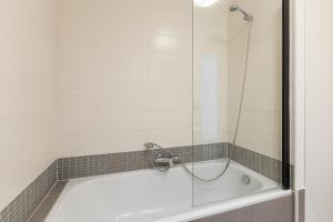 a bath tub with a glass shower door at Plaza in Sint-Idesbald +11 photos