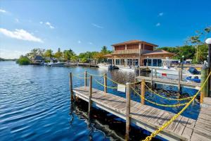 a dock with a house and boats on the water at New Tiny Home- Paddle Boards, Kayaks, Pool, Marina in Key Largo