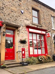 a brick building with a red door and window at La Casa De Campo in Long Preston
