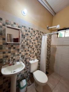 Un baño con inodoro, lavabo y ducha. en Posada El Encuentro, en Atyrá