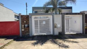 duas portas de garagem em frente a uma casa com uma palmeira em Casa c/ Churrasqueira a 550 m da Praia PDD0572 em Piçarras