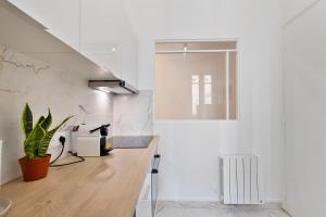 Una cocina con paredes blancas y una encimera con una planta en 3P Cosy proche Paris La Défense Fondation LV, en Suresnes 9 fotos más