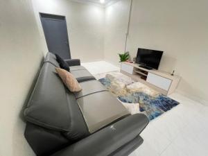 un salon avec un canapé gris et une télévision dans l'établissement AM Homestay, à Kota Bharu