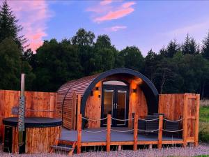 a circular house with a deck and a table and chairs at Barn Owl Pod - Speyside in Carron