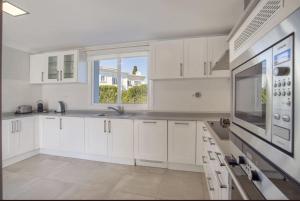 eine weiße Küche mit weißen Schränken und einem Fenster in der Unterkunft Elegant Villa Retreat with Lush Gardens in Marbella