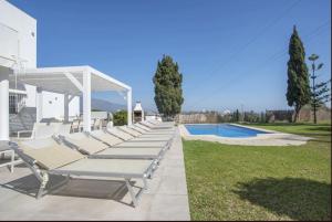 eine Reihe von Liegestühlen neben einem Swimmingpool in der Unterkunft Elegant Villa Retreat with Lush Gardens in Marbella