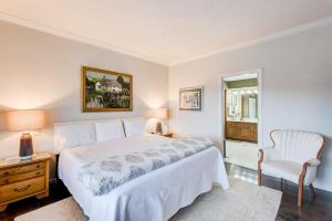 a bedroom with a white bed and a chair at Chetola: Robin 1 in Blowing Rock
