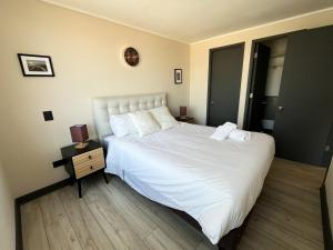 ein Schlafzimmer mit einem großen weißen Bett und einem Nachttisch in der Unterkunft Apartamento en Ñuñoa, estacionamiento, Estadio Nacional, Piscina in Santiago + 14 Fotos