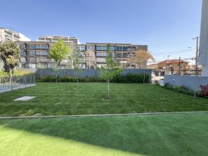 zwei Bäume in einem Hof mit Gebäuden im Hintergrund in der Unterkunft Apartamento en Ñuñoa, estacionamiento, Estadio Nacional, Piscina in Santiago