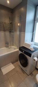 a washing machine in a bathroom with a shower at Zacisze by the Park in Szczawno-Zdrój
