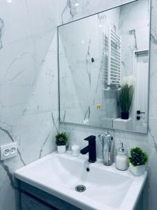 a white bathroom with a sink and a mirror at Lumiere in Aktau