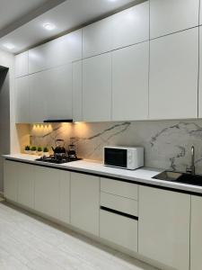 a white kitchen with white cabinets and a microwave at Lumiere in Aktau