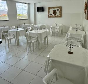 a dining room with white tables and chairs at Hotel Ideal in Jequié