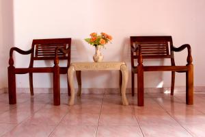 dos sillas y una mesa con un jarrón de flores en Holiday Guest Inn, en Negombo