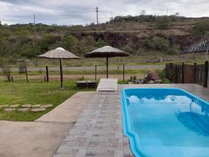 a swimming pool with two umbrellas in a yard at Casa Cabana Harmonia in Santana do Livramento