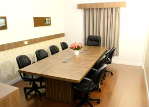 a conference room with a large wooden table and chairs at Strassen Hotel in Goiânia