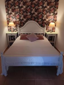 a bedroom with a white bed with two tables at O Cantinho de Góis in Góis