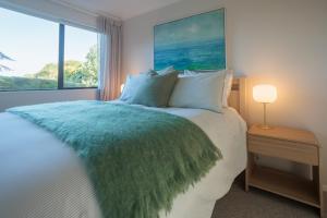 Un dormitorio con una cama con una manta verde y una ventana. en Lighthouse Apartment - Tūtūkākā, en Tutukaka