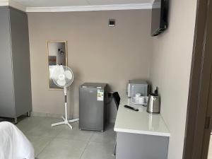 a room with a refrigerator and a fan at Vation Nation Guest House in Mokopane +13 photos
