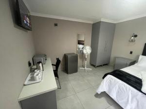 a bedroom with a bed and a desk and a sink at Vation Nation Guest House in Mokopane