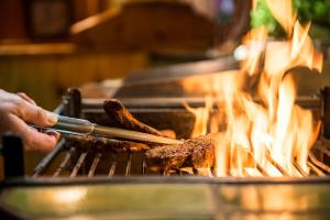 eine Person, die Fleisch auf einem Grill mit Flammen grillt in der Unterkunft Trip Inn Stadthotel Coburg in Coburg
