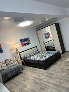 a bedroom with a bed and a couch at Однокомнатная квартира в центре города in Balqash