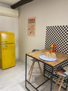 a kitchen with a table and a yellow refrigerator at Le pop Daudet in Fontvieille