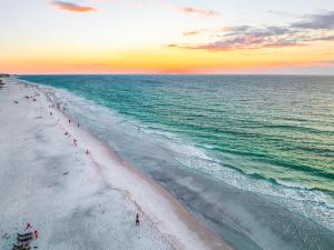 un gruppo di persone che camminano sulla spiaggia al tramonto di Beach Side Paradise - Luxury Home on the Beach a Ilexhurst