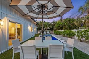 a patio with a table and chairs and an umbrella at Honey I'm Holmes - New Home Near the Beach Turf in Anna Maria Island