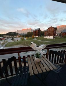 a wooden table with a vase of flowers on a balcony at cosystudio Superdevoluy 5pers pied des pistes in Le Dévoluy