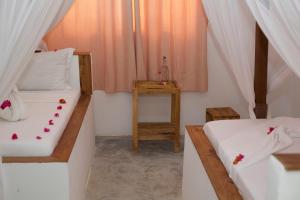 two beds in a room with a table at Barabara House in Jambiani