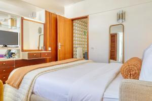 a bedroom with a bed and a tv and a chair at Aida's Place, a Home in Madeira in Ilhéu do Gorgulho