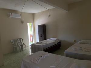 a room with two beds and two chairs in it at Hotel Renascer pojuca in Pojuca