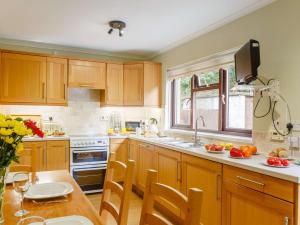 a kitchen with wooden cabinets and a table with a bowl of fruit at 4 Bed in Harlech 89631 in Harlech +11 photos
