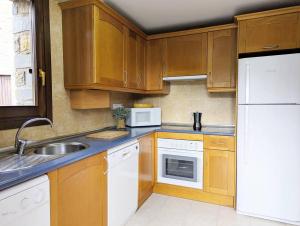a kitchen with wooden cabinets and a white refrigerator at Pacino views l wifi l garaje l terraza l vistas in Sallent de Gállego