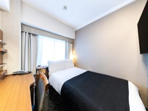 a hotel room with a bed and a desk and a window at APA Hotel Tennoji Ekimae in Osaka
