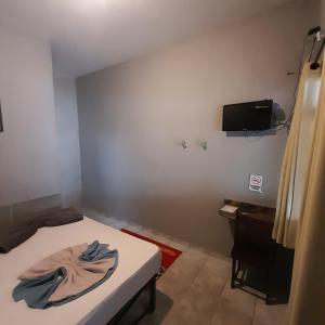 um quarto com uma cama e uma TV na parede em Pousada Rout Bikers Penedo em Penedo