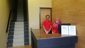 a man and a woman standing behind a counter at Hotel Iskandar in Kota Kinabalu