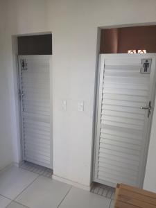 two white doors in a room with white tile floors at Pousada Costeira Barra do Sul in Balneario Barra do Sul +2 photos